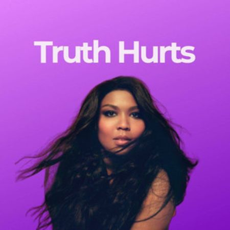 singer lizzo sits infront of a purple back drop with her long hair flowing in the air. on the top of the picture it says 'Truth hurts' 